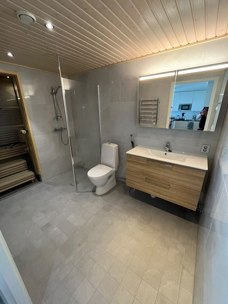 Kylpyhuone puukatolla, lavuaarilla ja seinä-WC:llä