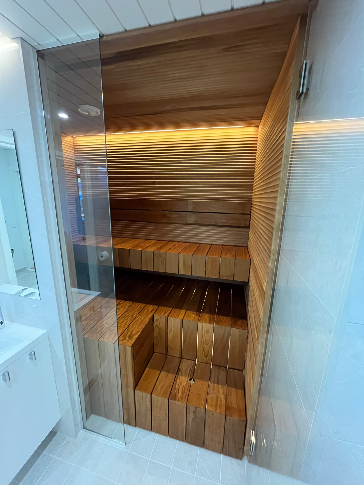 Remontoitu sauna lasiovella ja epäsuoralla valaistuksella
