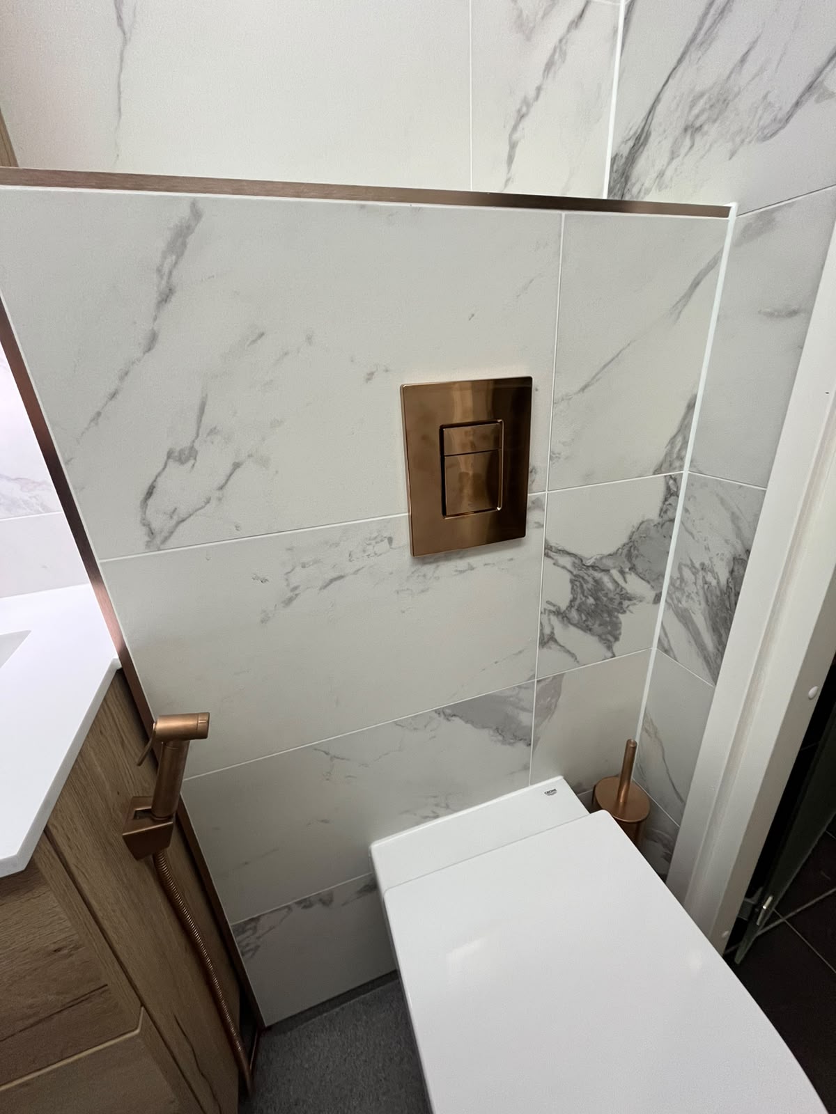 Seinä-WC ja kuparinen huuhtelupainike
